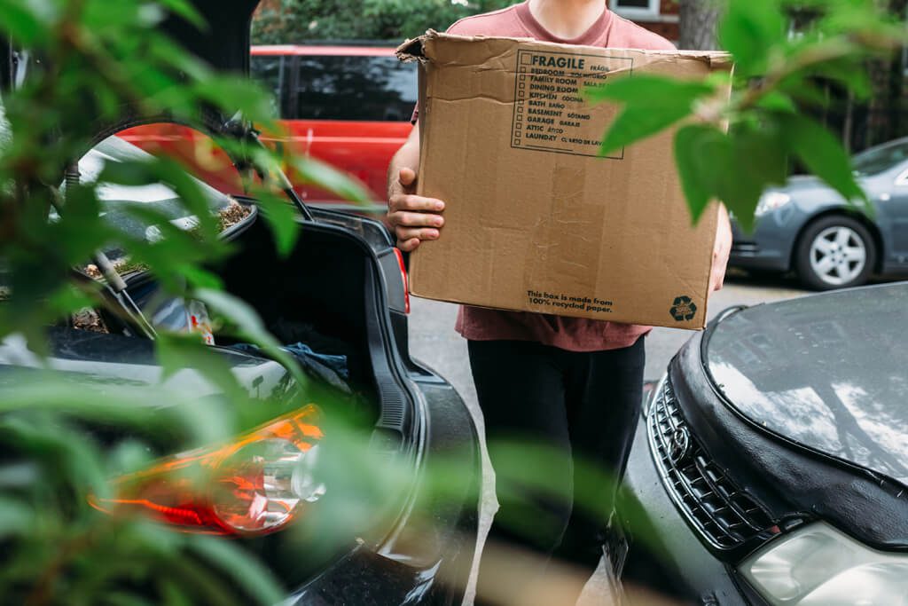 Young man carrying box into new home