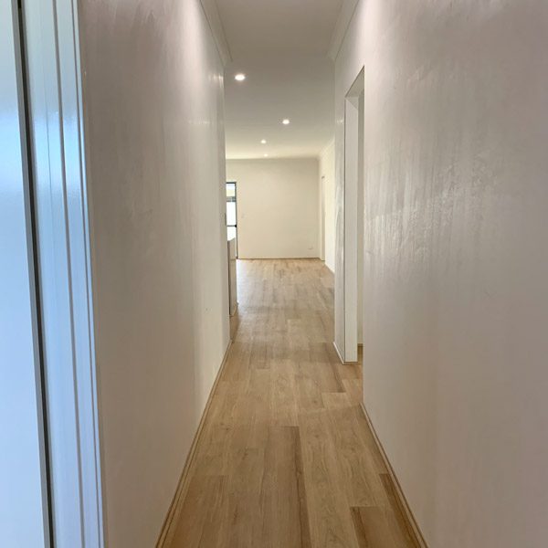 unfurnished hallway with timber floors