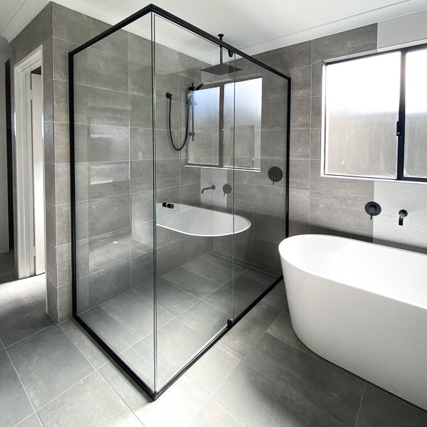 A black framed shower with a free standing bath and rain shower head by Move Homes