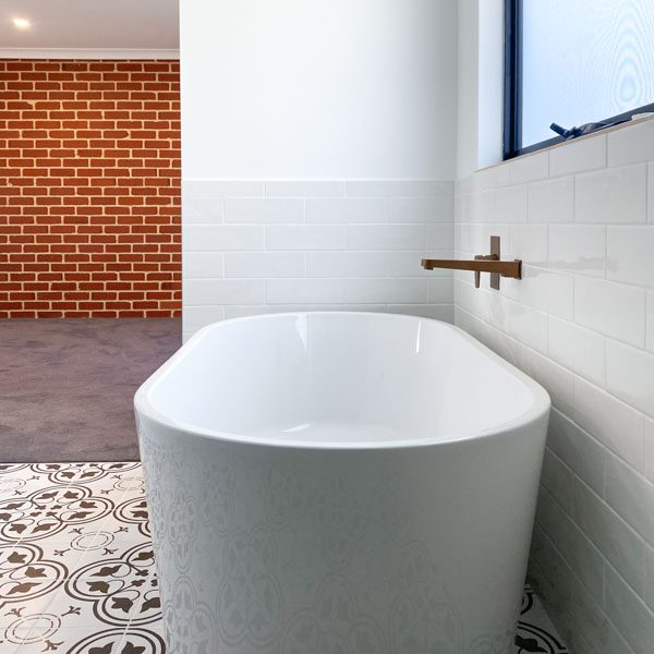 Ensuite of a new home with a free standing bath and brick wall